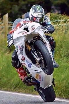 a man riding on the back of a white motorcycle down a curvy road