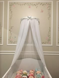 a baby crib with stuffed animals in it and a white canopy over the bed