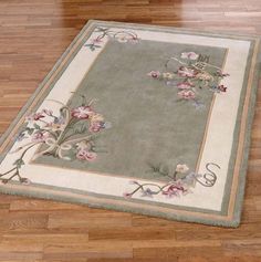 an area rug with flowers and vines on the floor in front of a wooden floor