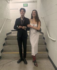 two people standing in front of some stairs