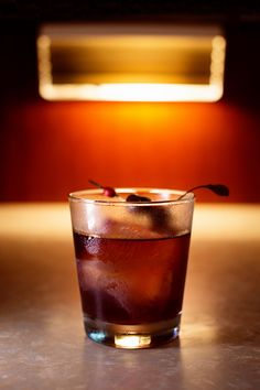 a close up of a drink on a table with a light in the back ground