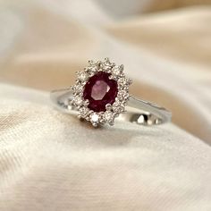 a close up of a ring with a red stone in it on a white cloth