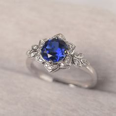 ◆The ring draws inspiration from the polaris. Hand-finished in Sterling sliver, this piece features a round shaped sapphire. Clear zirzons decorate around the main stone. An extremely simple celestial ring that you cannot miss. ◆ Production Description: Main stone Type: Lab Sapphire Main Stone Shape: Round Main Stone Size:7*7mm(1.66ct) Side stone: CZ Metal: 925 Sterling silver - Other options available in the drop down menu ◆ Customization: √Free for Add Engraving √Other Metal Type Available √Ot Fine Jewelry Sapphire Topaz Round Ring, Sapphire Ring White Gold, Sapphire Color Topaz Ring With Brilliant Cut, Dazzling Round Lab-created Sapphire Rings, Classic Round Gemstone Flower Ring, Sapphire Halo Ring With Lab-created Gemstone, Anniversary Halo Ring With Lab-created Sapphire, Elegant Silver Flower Ring With Birthstone, Elegant White Gold Flower Ring With Birthstone