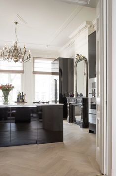 an elegant kitchen with black cabinets and chandelier