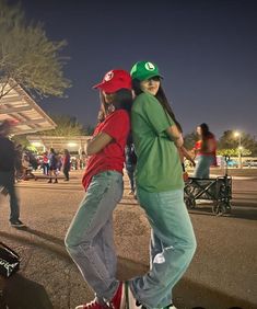 two young people riding skateboards on a city street at night, one holding the other's back