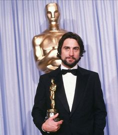 a man in a tuxedo holding an oscar award