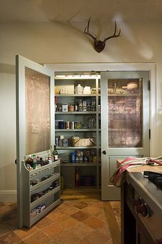 a kitchen with an open pantry in the corner and a deer head on the wall