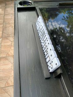 a white keyboard sitting on top of a wooden table next to a black window sill