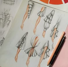 the drawing shows different types of dresses on paper with markers and pencils next to it