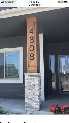 a house number sign on the front of a home with flowers in the foreground