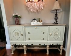 an old dresser is painted in pale blue and has pink crystal chandelier above it