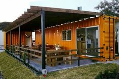 a house made out of shipping containers with a deck and dining area on the outside