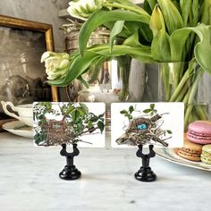 two bird's nest place cards are sitting on a table next to some flowers