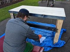 a man sitting at a table with blue tarp on the ground next to it