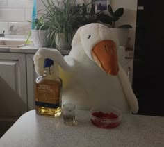 a stuffed duck sitting on top of a kitchen counter next to a bottle of whiskey