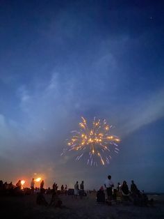 people are sitting on the beach watching fireworks