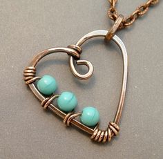 a heart shaped pendant with three beads hanging from it