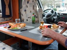 a man sitting at a table with plates of food in front of him on a bus