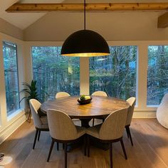 a dining room table with chairs and a lamp hanging from it's center point