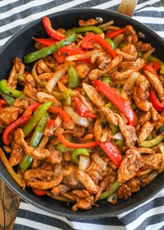 chicken fajita with peppers and onions in a skillet on a striped cloth