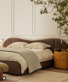 a bed sitting in the middle of a bedroom next to a plant