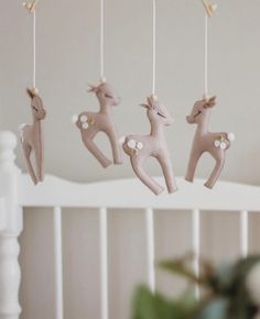 three wooden deer ornaments hanging from a white crib