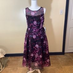 A Beautiful And Elegant Fit And Flare Dress With A Sultry Botanical Print In Plum, Rose, And Black. Sheer, Lightweight Floral Print Over Attached Black Lining. Invisible Back Zipper, Pleats At Waistline For Full Skirt. Flirty And Fun! Dressy Floral Print Midi Dress For Party, Purple A-line Dress For Night Out, Fitted Purple Midi Dress For Prom, Sheer Purple Party Dress, Purple Sheer Party Dress, Elegant Sheer Purple Dress, Elegant Purple Sheer Dress, Summer Purple Midi Dress For Formal Occasions, Purple Midi Dress For Summer Formal Events