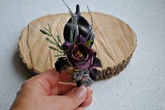 a person holding a flower in front of a piece of wood that has been cut into pieces