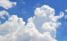 an airplane is flying in the blue sky with white fluffy clouds above it and below