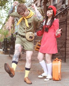 a man and woman dressed in costume walking down the street with suitcases behind them