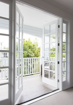 an open door leading to a porch with white walls and doors on both sides that lead outside