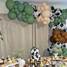 a table topped with desserts and balloons in the shape of cow's heads