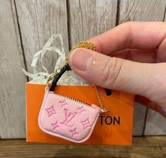 a person holding a pink purse keychain in their hand