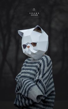 a person wearing a paper animal mask in front of a dark background with trees and branches