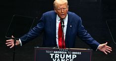 a man in a suit and tie standing at a podium with his hands out to the side