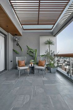 two chairs sitting on top of a patio next to plants