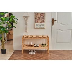 a wooden shoe rack sitting next to a door in front of a potted plant