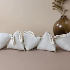 three pieces of white linen with tags on them sitting in front of a brown vase