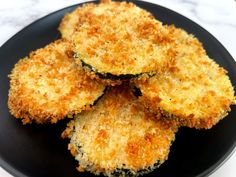 some fried food on a black plate on a white tablecloth and marble counter top