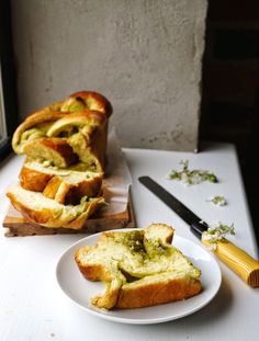 slices of bread with pesto spread on them next to a knife and cutting board