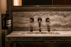 a marble sink with two faucets and soap dispensers on it