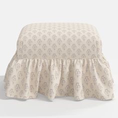 a white and beige ottoman with a ruffled skirt on it's bottom cover