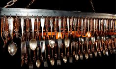 a chandelier with spoons and forks hanging from it's sides in the dark