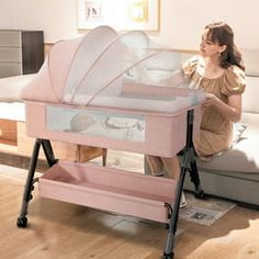 a woman sitting on a couch next to a pink baby crib in the living room