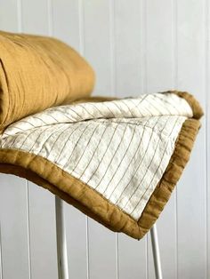 a brown and white blanket sitting on top of a metal chair next to a wall