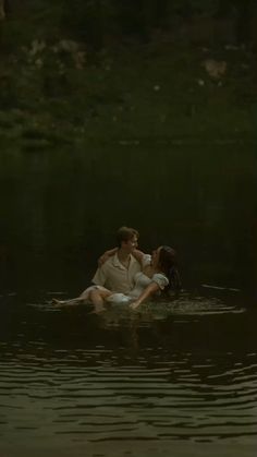 a man and woman are sitting in the water with their arms around each other as they kiss