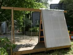 a swing set in the middle of a yard with a metal sheet covering it's back