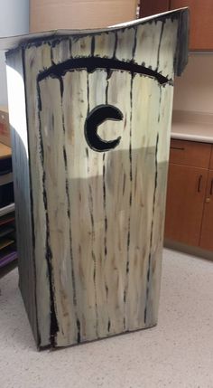 a cardboard box with the letter c painted on it in front of a desk area