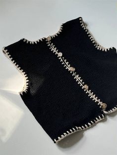 two pieces of black cloth with white stitches on the edges and beading around the edges