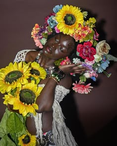 a woman with sunflowers on her head is holding a bunch of flowers in front of her face